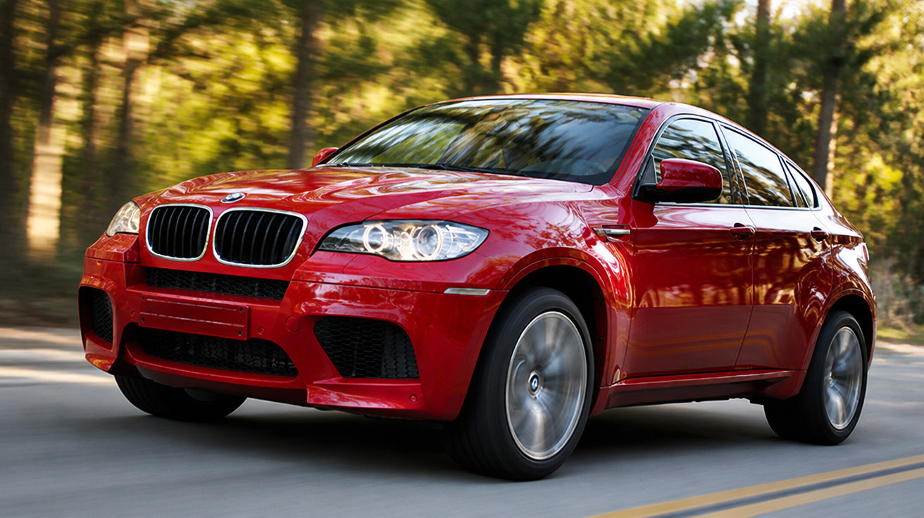 Carro BMW vermelho em movimento numa estrada rodeada de árvores verdes.