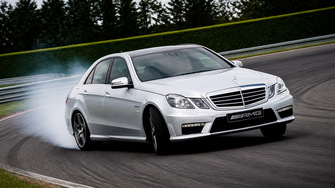 Mercedes-Benz AMG prata a fazer derrapagem numa curva de uma pista de corrida.
