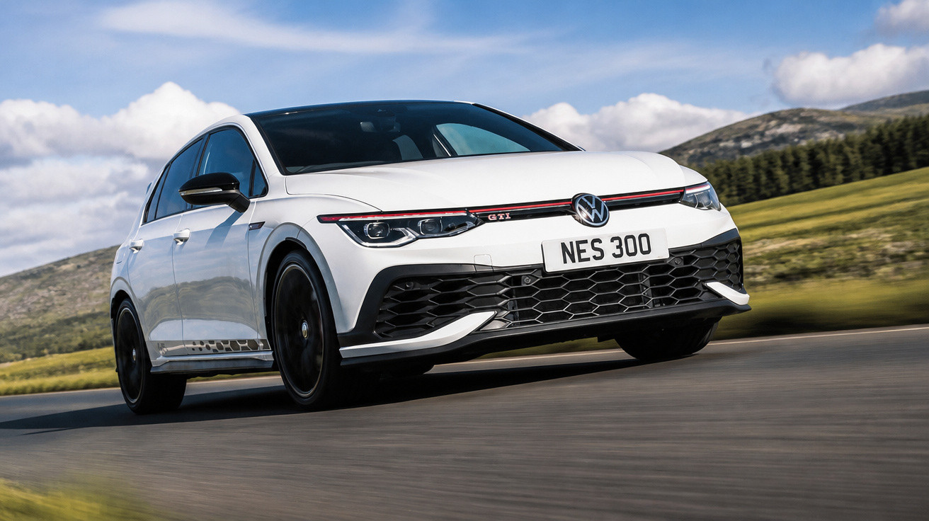 Carro branco Volkswagen Golf GTI em movimento numa estrada com paisagem natural ao fundo.