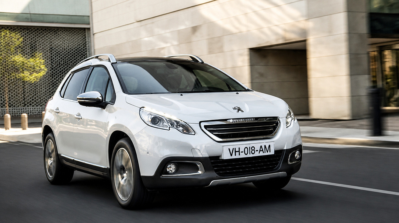 Automóvel Peugeot branco em movimento numa rua urbana com edifícios modernos ao fundo.