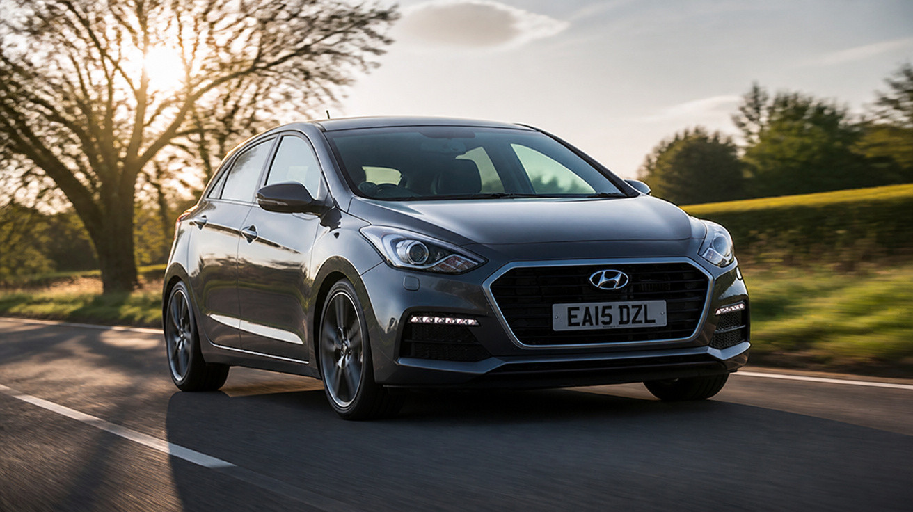 Carro cinzento Hyundai em movimento numa estrada com paisagem rural ao entardecer.