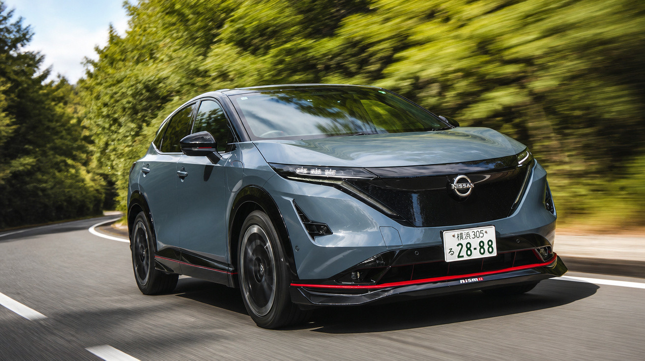 Carro elétrico Nissan Juke cinzento a circular numa estrada rodeada de árvores verdes.