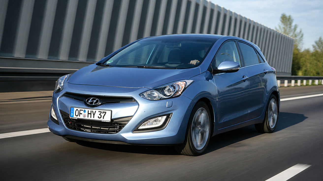 Carro Hyundai azul a circular numa estrada com barreira de proteção e edifício no fundo.