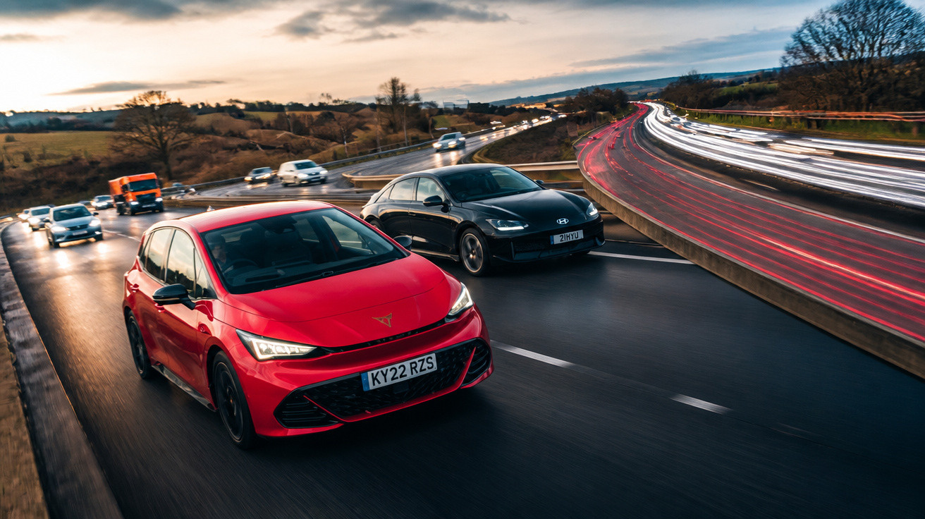 Dois carros modernos, vermelho e preto, a circular numa autoestrada ao entardecer com luzes das viaturas em movimento.
