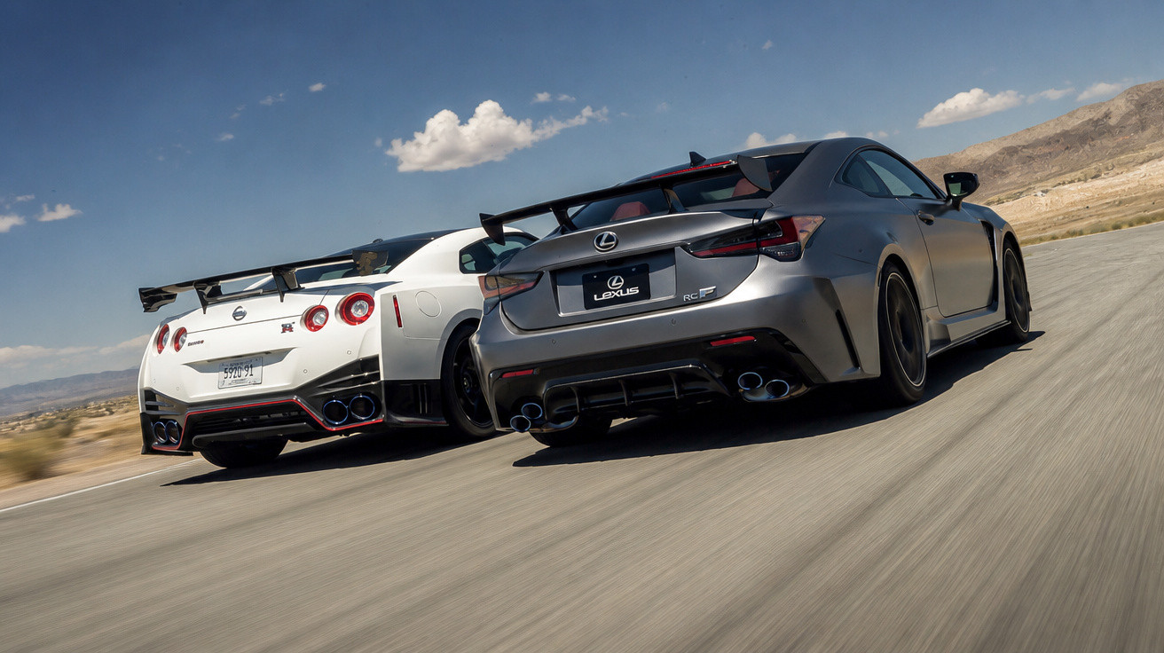 Dois carros desportivos, um branco Nissan GT-R e um cinzento Lexus RC F, a acelerar numa estrada deserta.