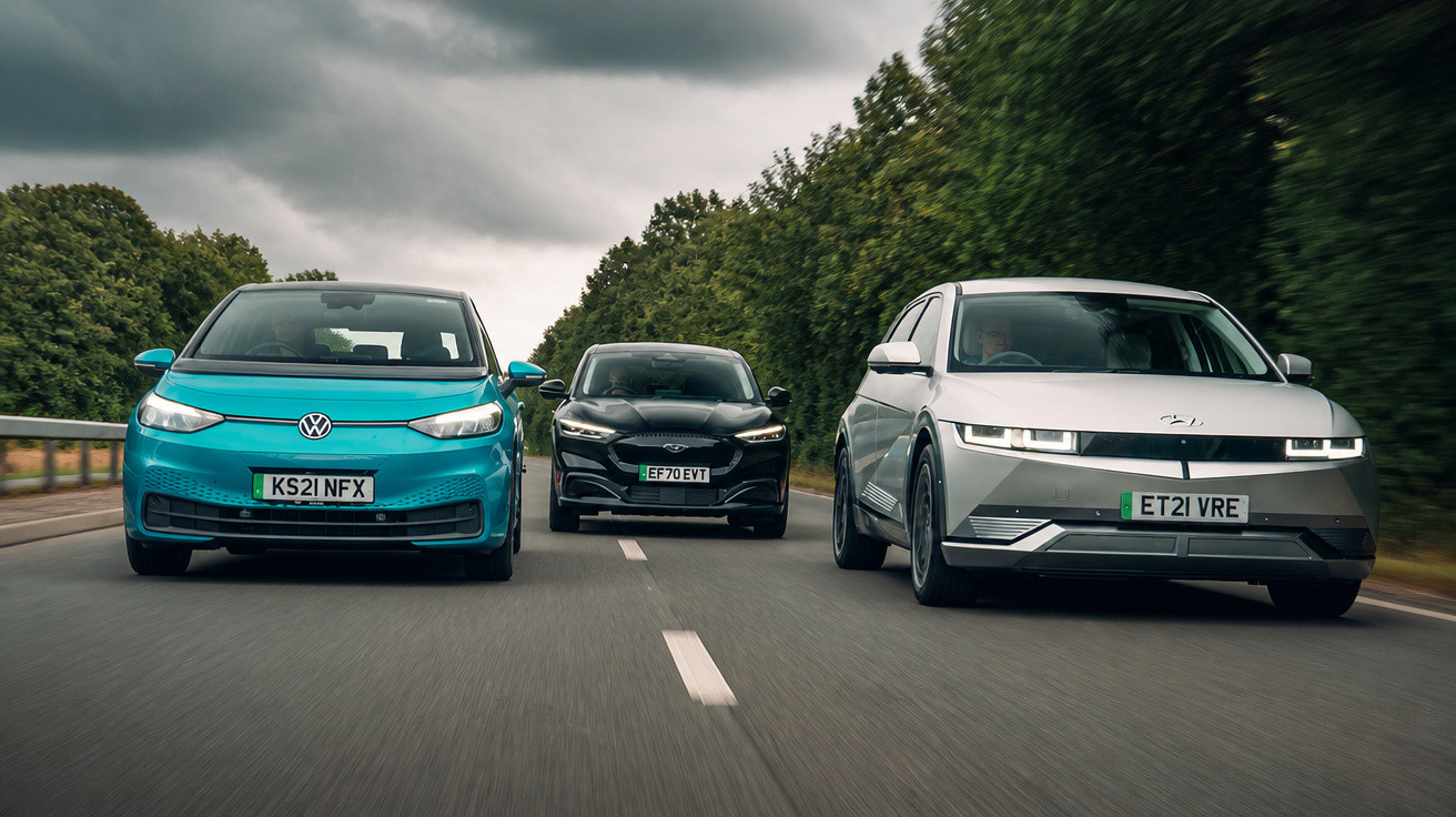 Três carros elétricos a circular lado a lado numa estrada rodeada de árvores sob céu nublado.